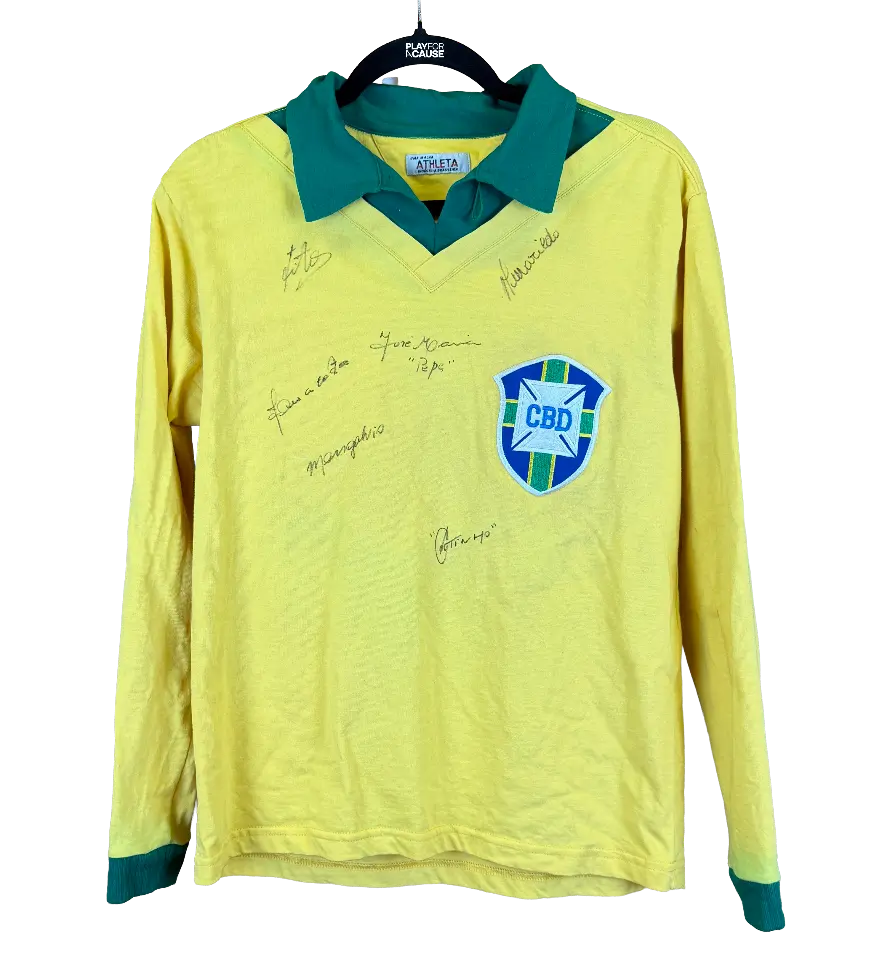 announcements/26e7ad61-d693-4415-97af-d80c3eff8552/1789387835536-camisa-brasil-garrincha-autografada-pelos-campeoes-1.webp